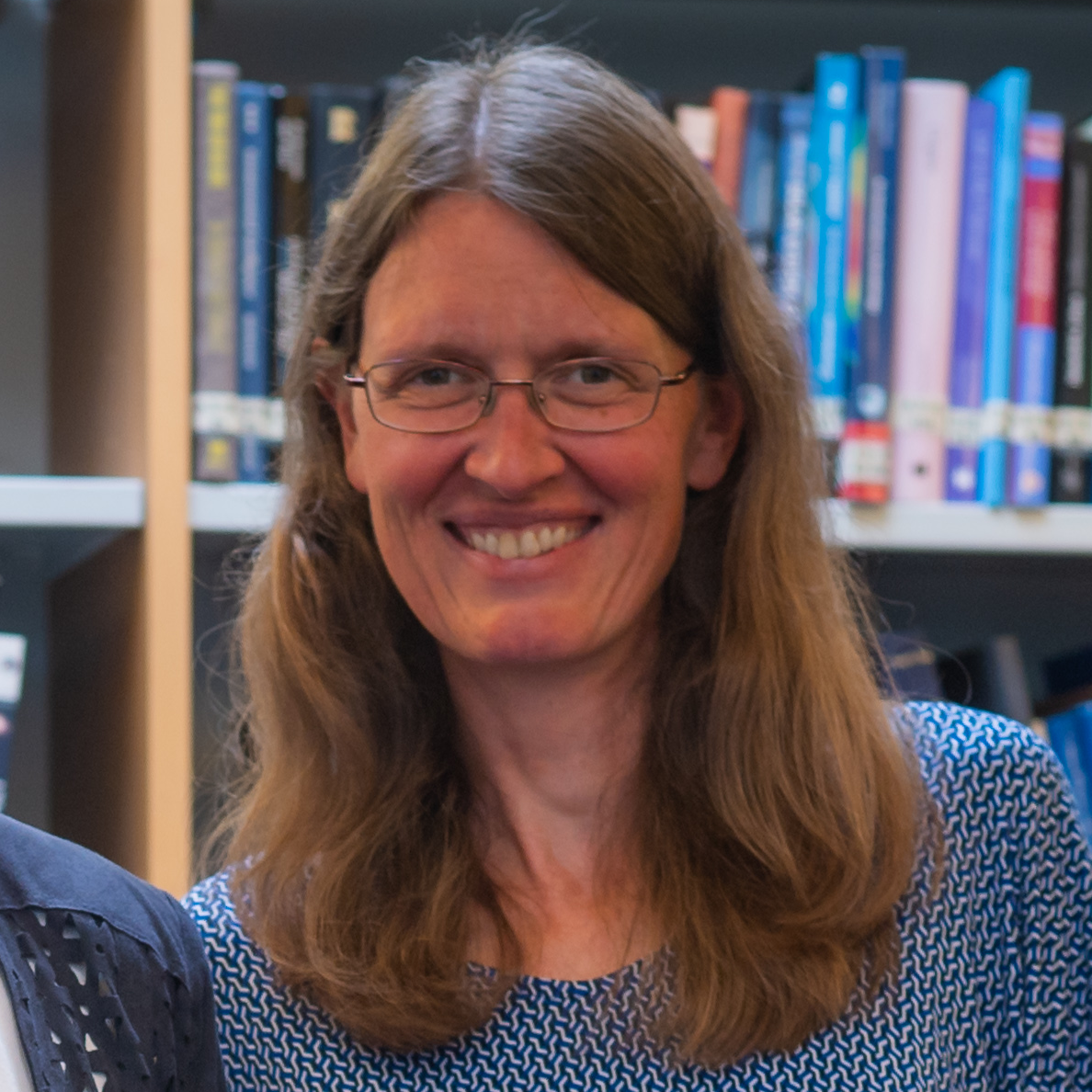 headshot of Silvia Meakins with books on shelves in background